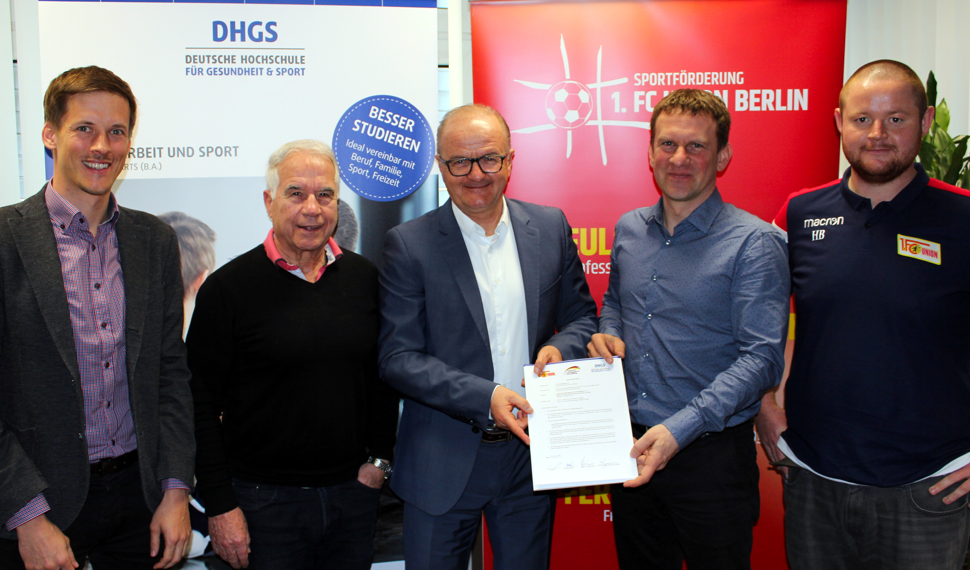 Fünf männliche Personen mit einem Kooperationsvertrag zwichen der DHGS Hochschule und dem 1.FC Union Berlin