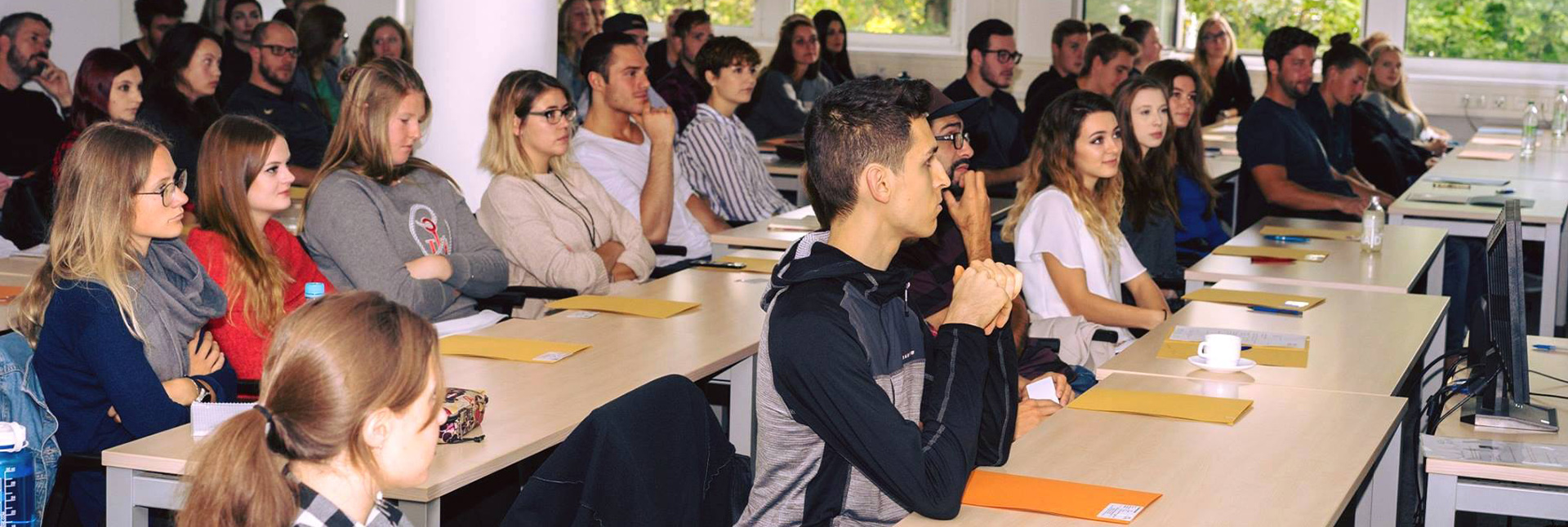 Studenten blicken interessiert nach vorne zum Dozenten.