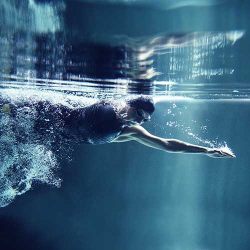 Eine Schwimmerin durchbricht das Wasser mit kraftvollen Schwimmzügen.