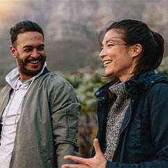 Eine junge Frau und ein Mann lächeln in ein Gespräch vertieft.