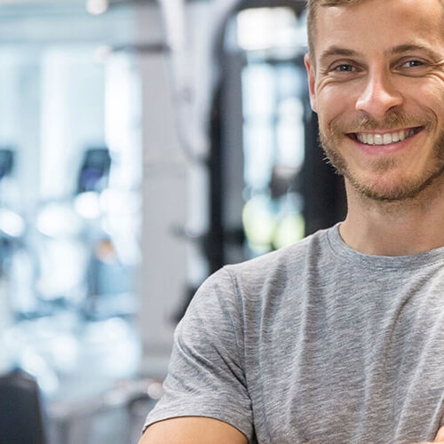 Lächelnder, junger Mann im Fitnessstudio.