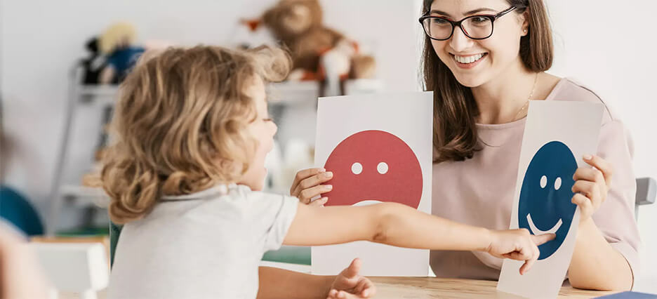 Pädagogin unterrichtet Kleinkind in der Erkennung von Emotionen.