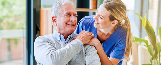 Pflegerin legt Hand auf Schulter von älterem Patienten.