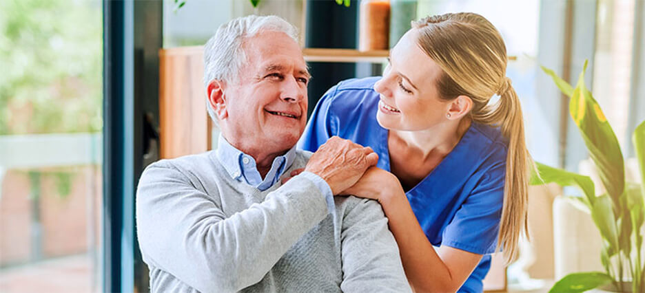 Pflegerin legt Hand auf Schulter von älterem Patienten.