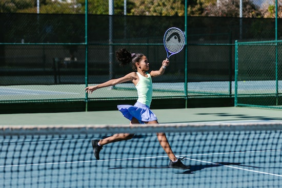 Mädchen retouniert einen Ball beim Outdoor-Tennis.