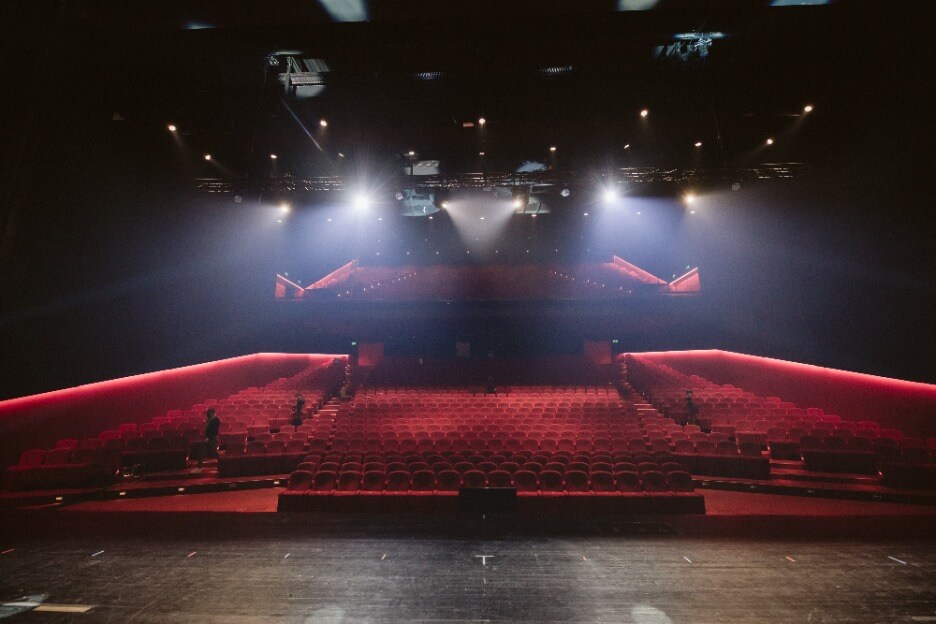 Großes Auditorium mit roten Stühlen und Scheinwerferlicht