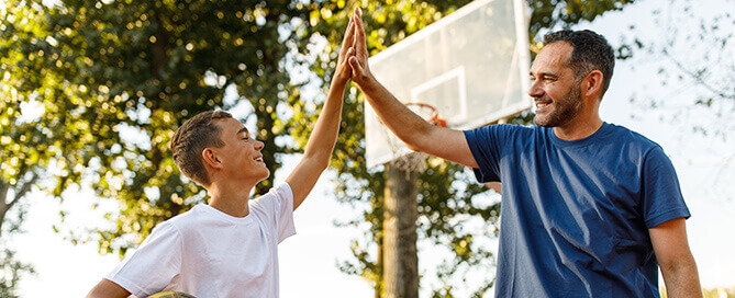 Sozialarbeiter spielt mit Kind Basketball