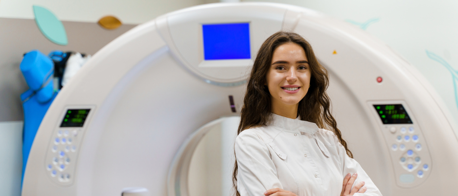 Medizintechnikerin steht vor einem Computertomographen.