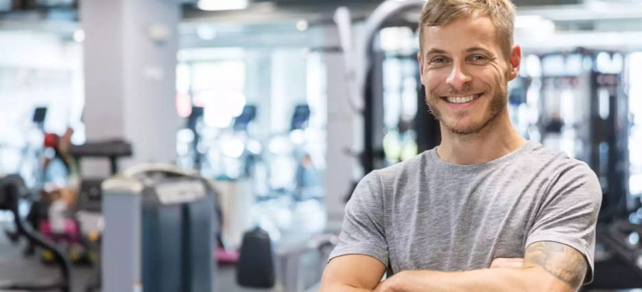 Junger Fitnessanlagenmanager lächelt in die Kamera.