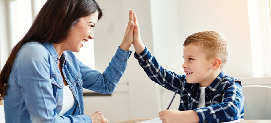 Sozialarbeiterin gibt einem kleinen Jungen ein High five. Sozialarbeiterin gibt einem kleinen Jungen ein High five.