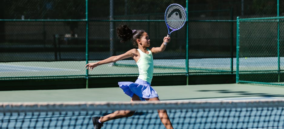 Mädchen retouniert einen Ball beim Outdoor-Tennis.