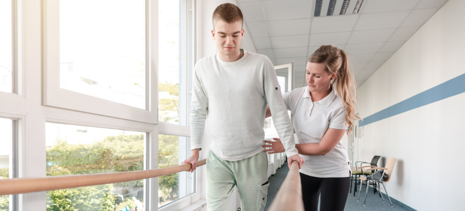 Übungsleiterin hilft einem Patienten bei der Rehabilitation.