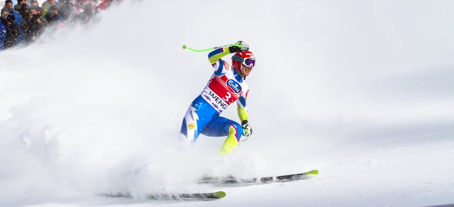 Skifahrer fährt mitten im Rennen den Berg hinunter.
