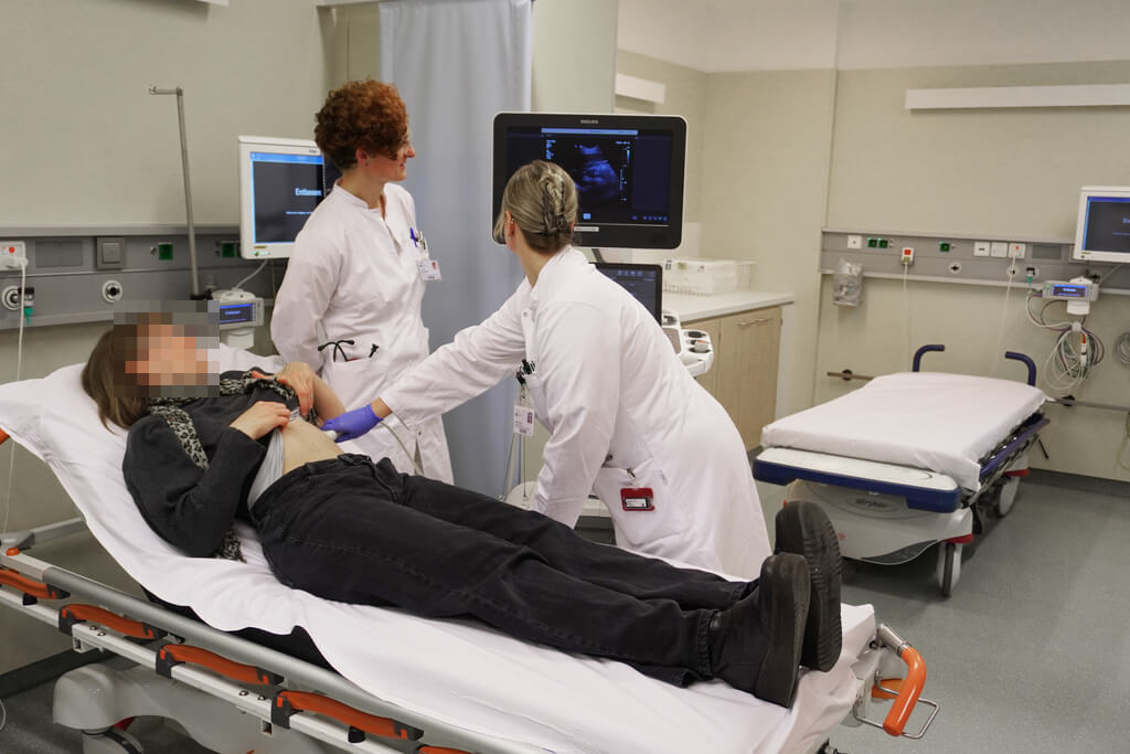 Eine Physician Assistant führt eine Ultraschalluntersuchung durch, um innere Organe einer Patientin zu beobachten