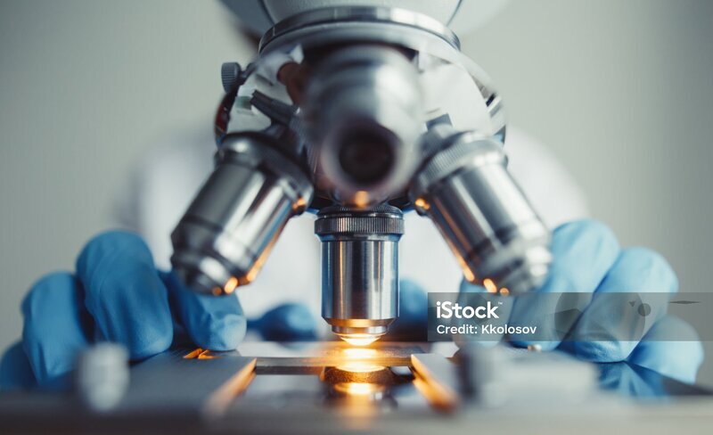 Close up of examining of test sample under the microscope in laboratory.